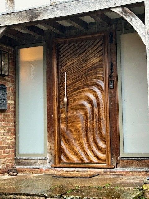 Bespoke carved timber entrance door with flowing wood grain by LUX Bespoke Doors
