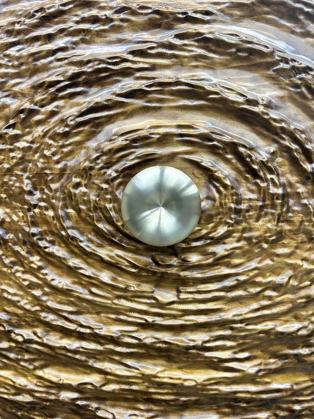 Hand-carved rippled door surface with a brushed metal detail